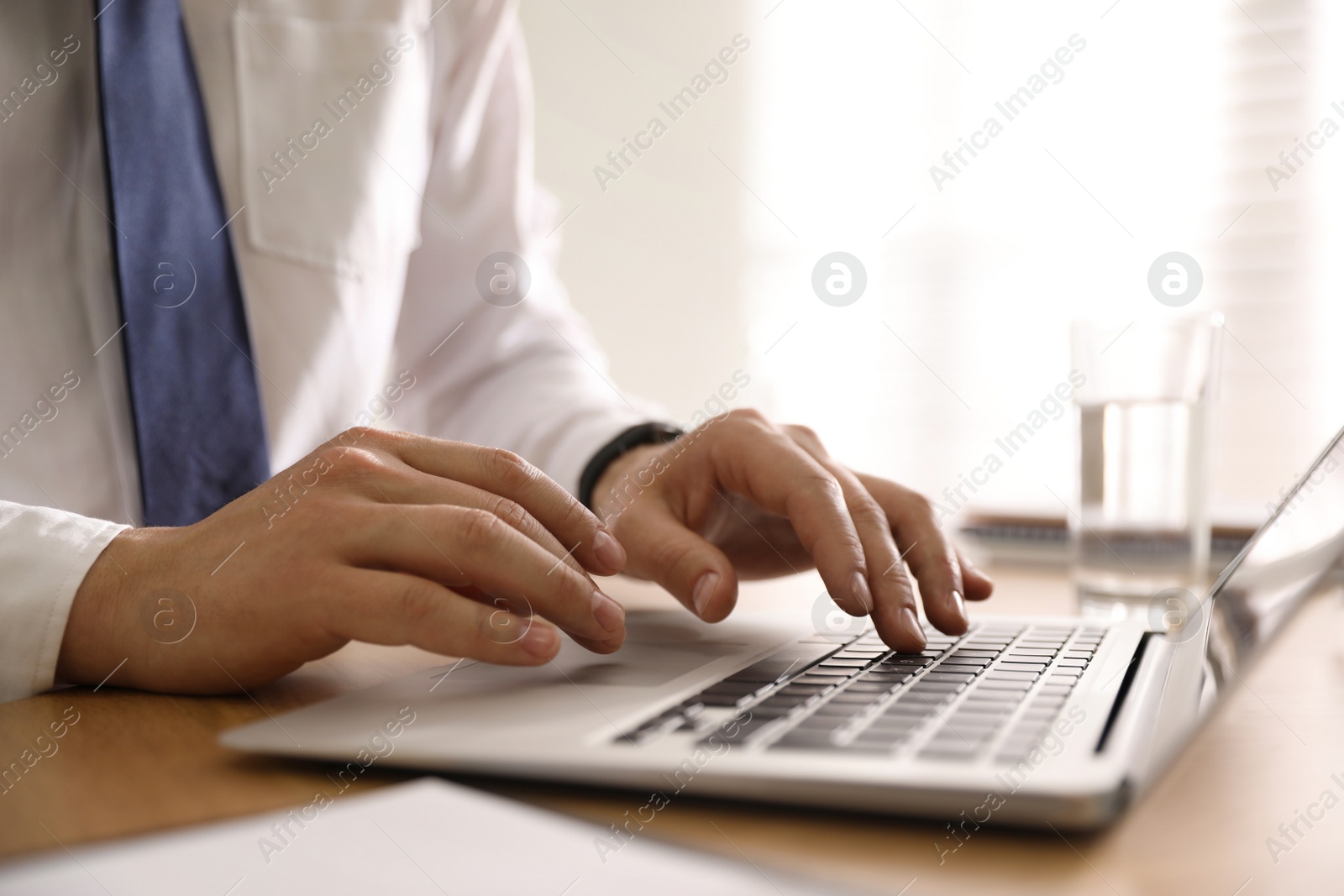 Photo of Man working with laptop in office, closeup of hands