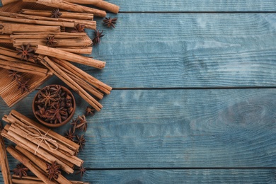 Photo of Aromatic cinnamon sticks and anise on blue wooden table, flat lay. Space for text