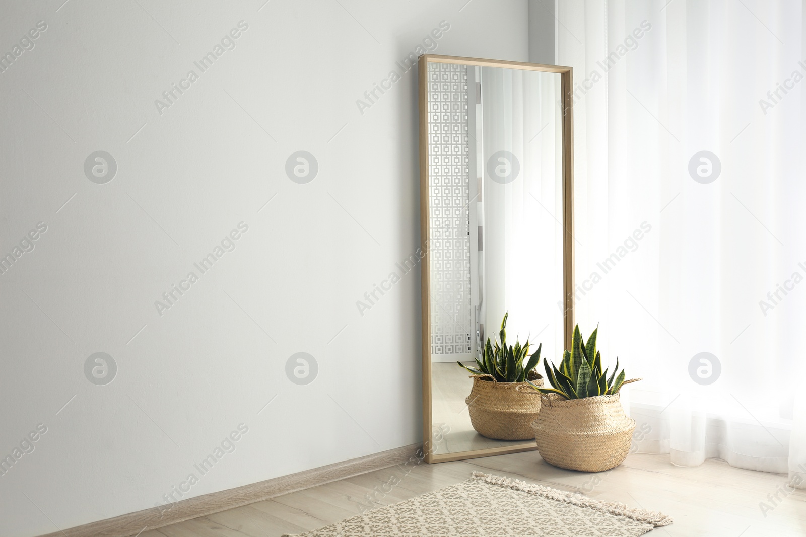 Photo of Large mirror with wooden frame near window in light room