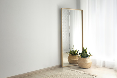 Large mirror with wooden frame near window in light room