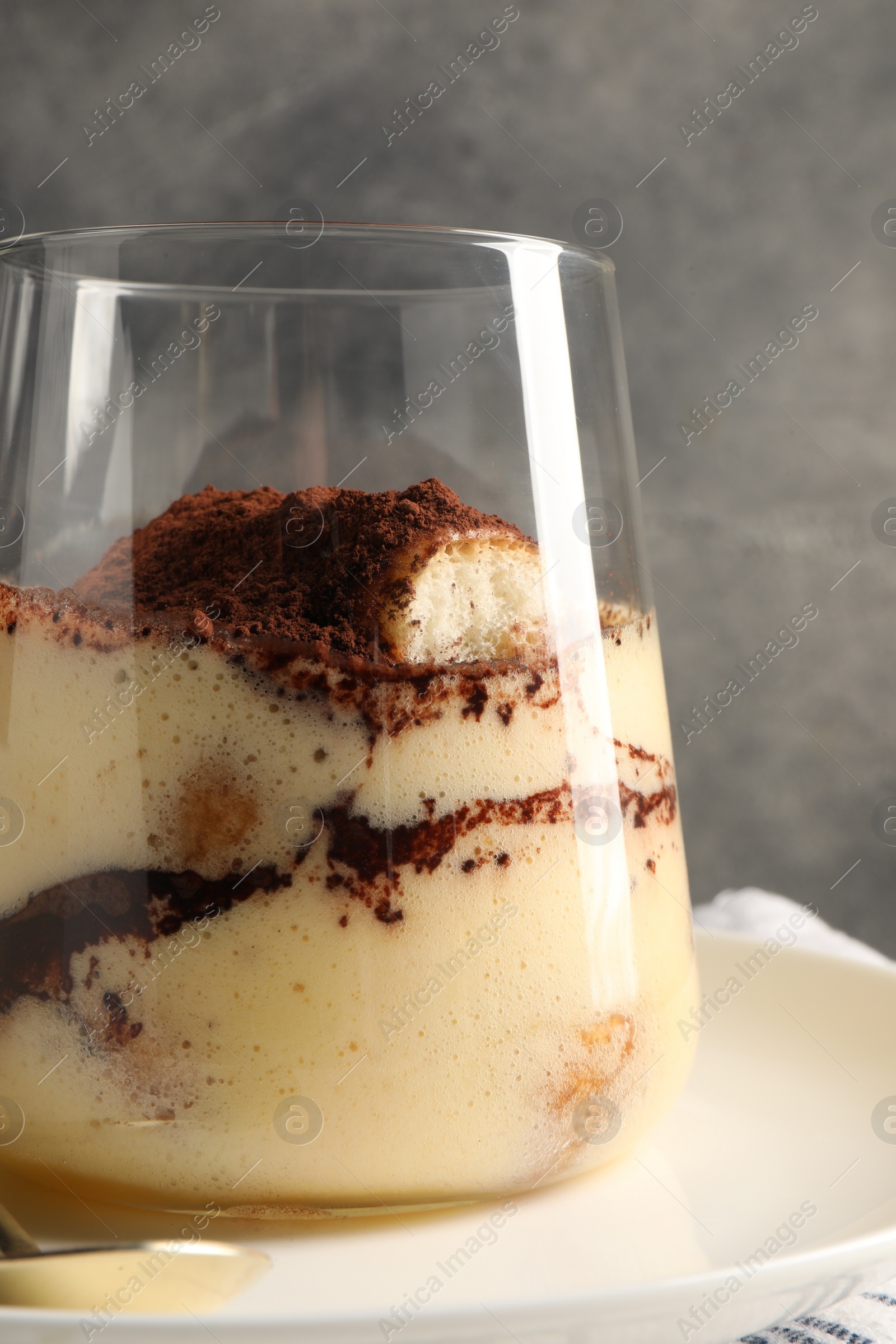 Photo of Delicious tiramisu in glass on plate, closeup