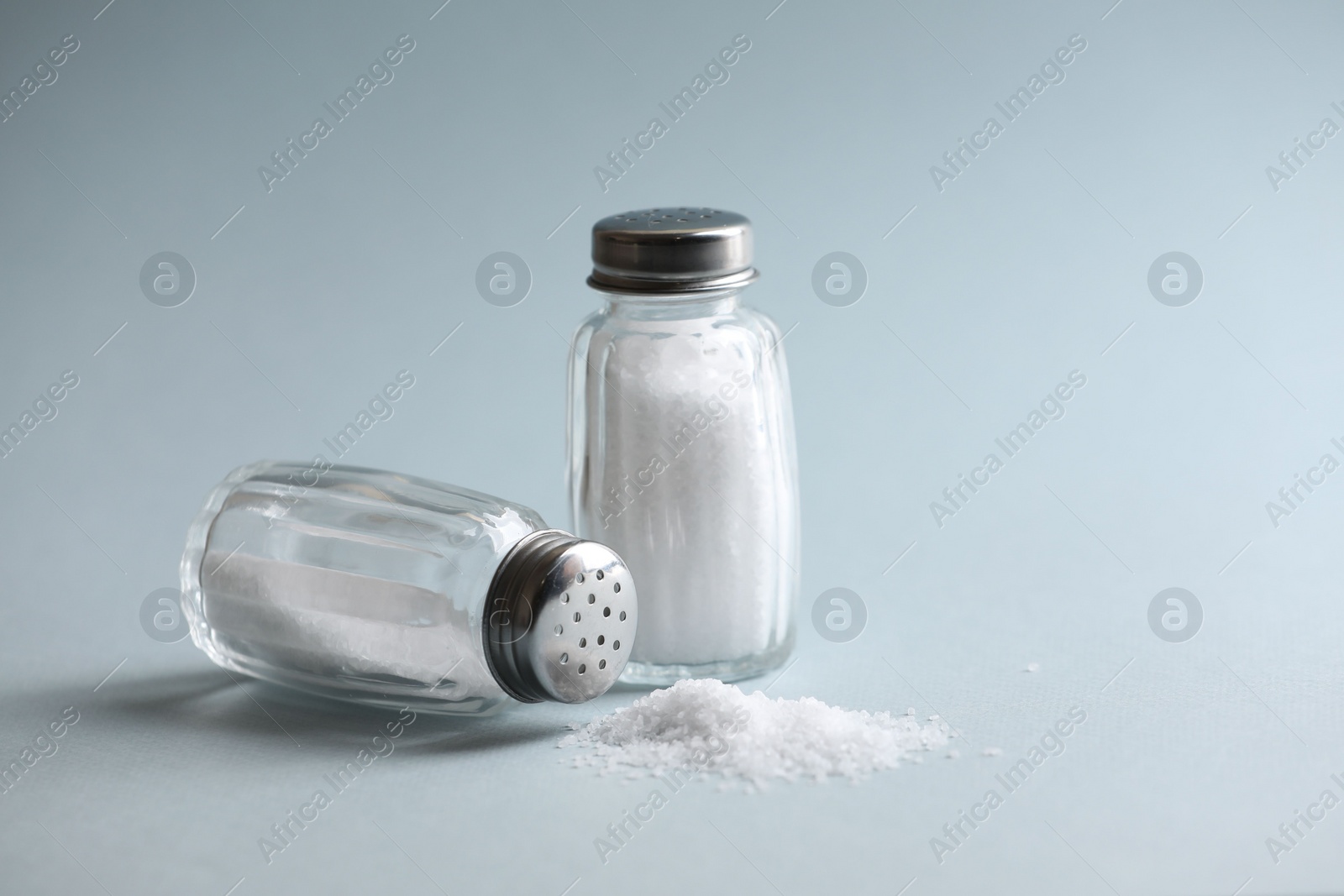 Photo of Natural salt in shakers on color background, space for text