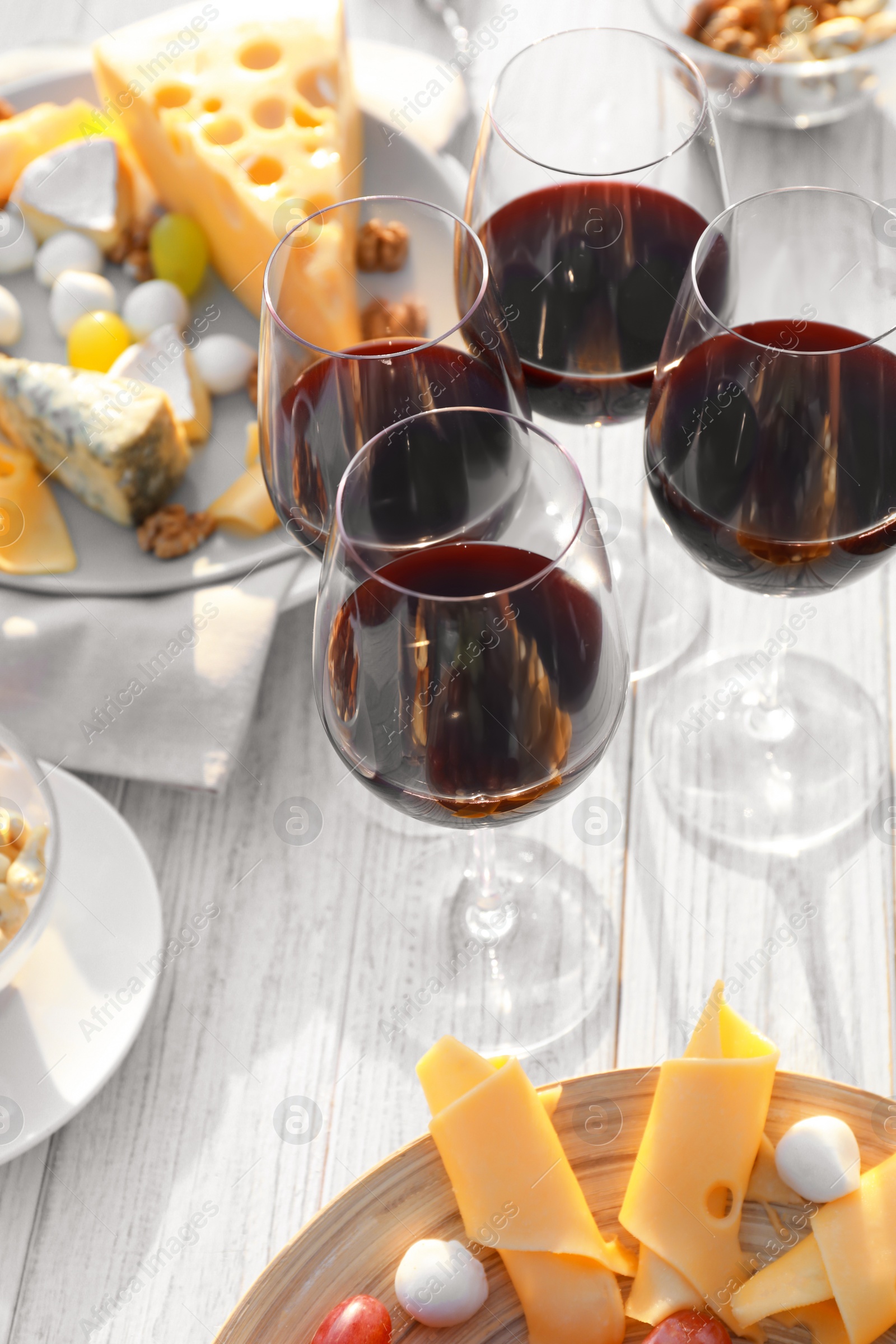 Photo of Red wine and snacks served for picnic on white wooden table