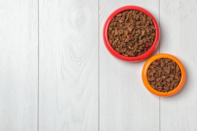 Bowls with food for cat and dog on wooden background. Pet care