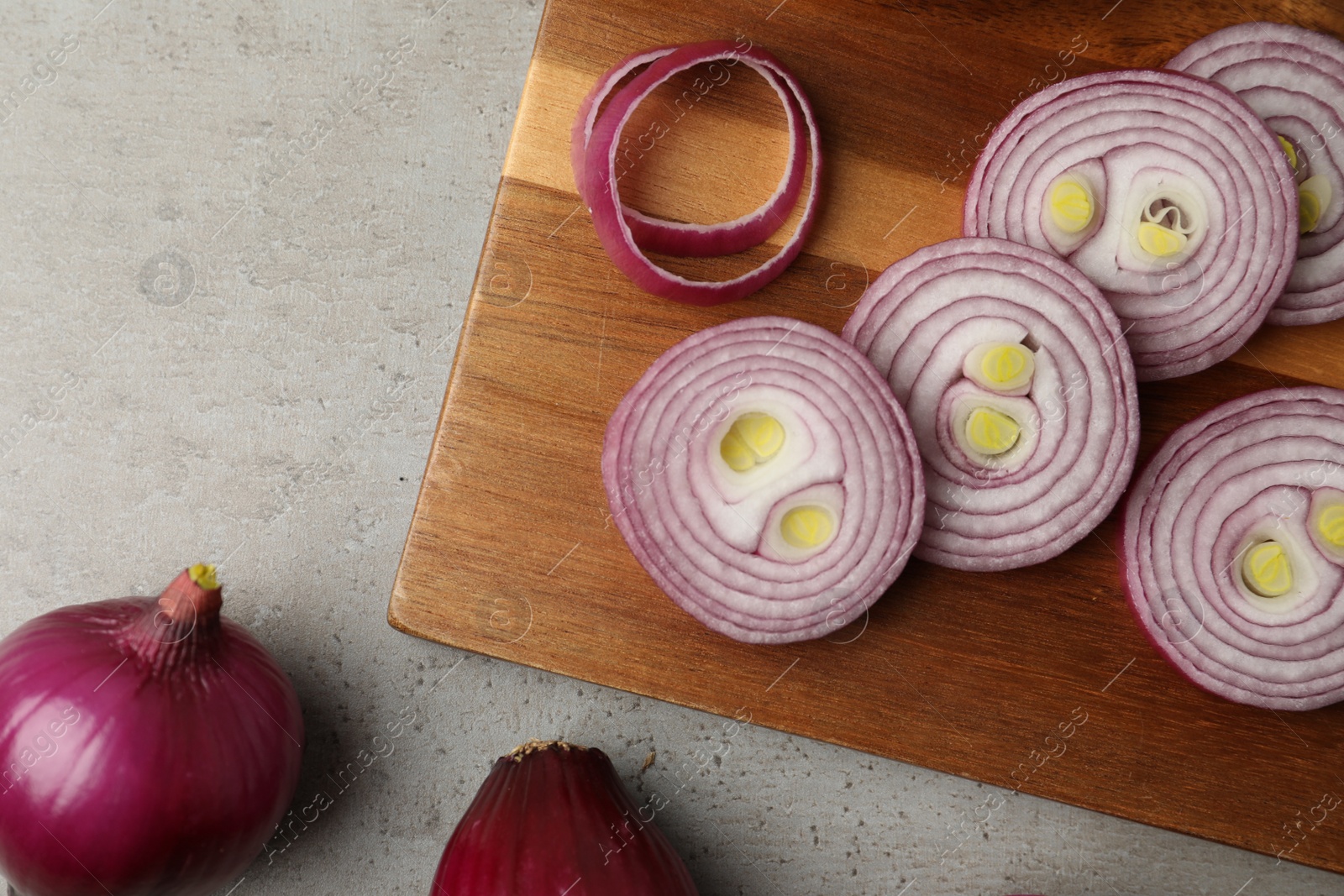 Photo of Red onion and wooden board on light grey table, flat lay