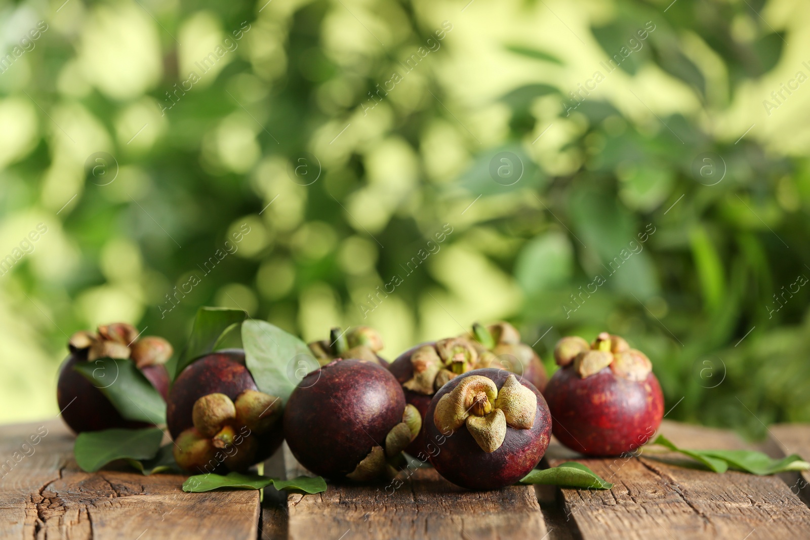 Photo of Delicious tropical mangosteen fruits on wooden table. Space for text