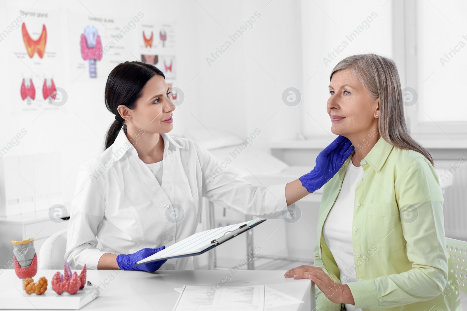 Photo of Endocrinologist examining thyroid gland of patient at table in hospital