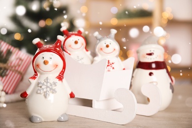 Cute decorative snowmen on table against blurred background