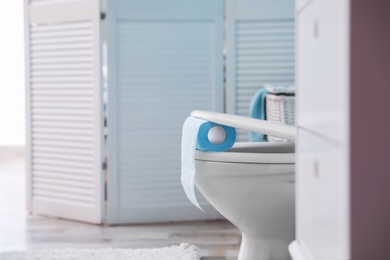 Photo of Toilet bowl with paper roll in bathroom. Space for text