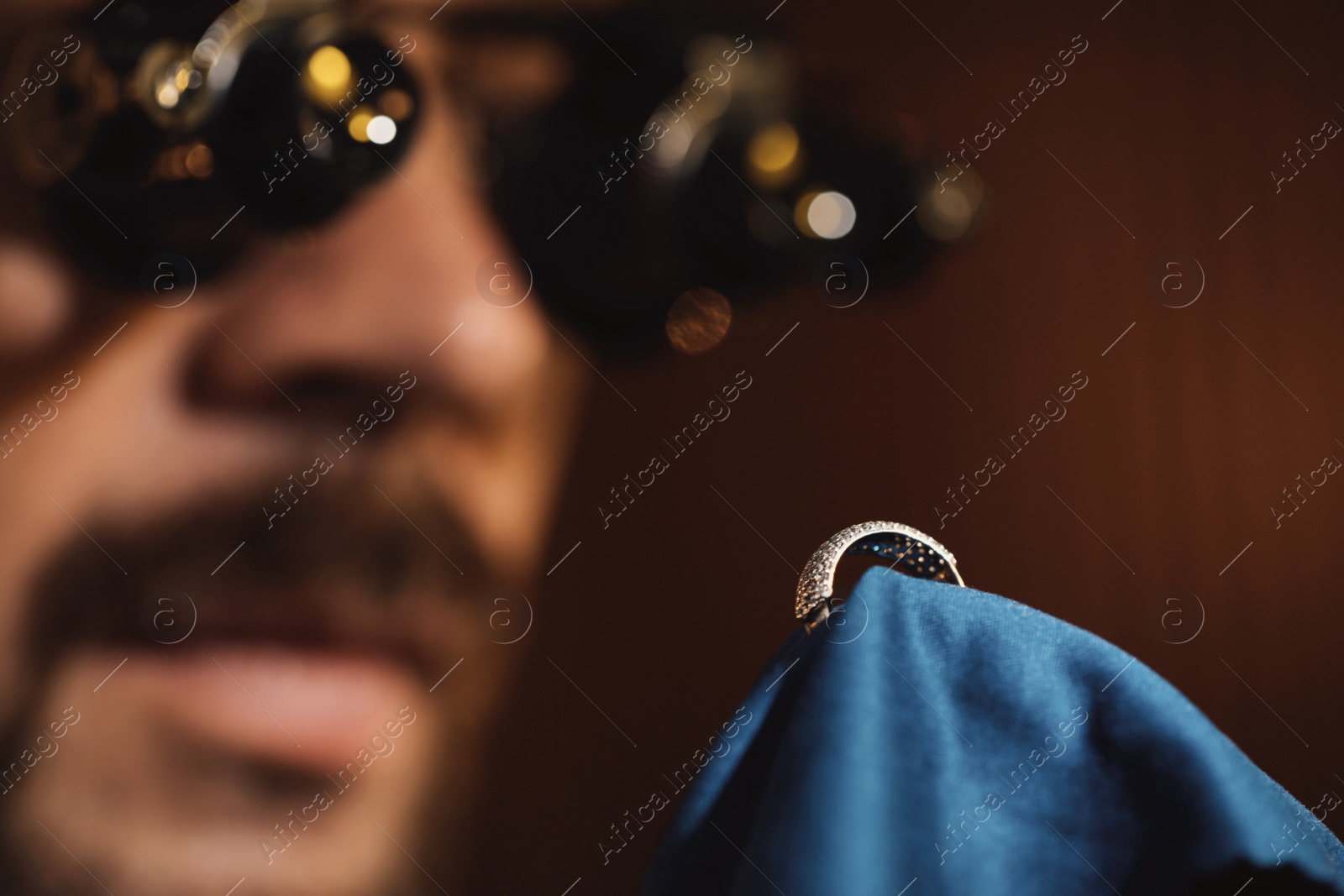 Photo of Jeweler working with ring on blurred background, closeup