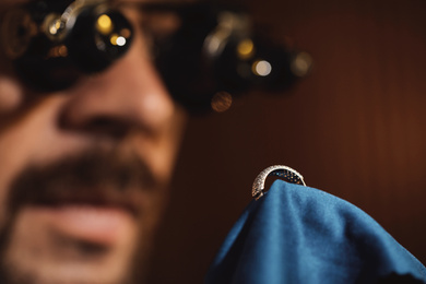 Photo of Jeweler working with ring on blurred background, closeup