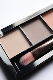 Photo of Beautiful eye shadow palette with brush on white table, above view
