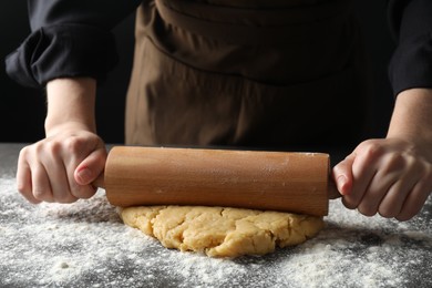 Photo of Making shortcrust pastry. Woman rolling raw dough at table, closeup