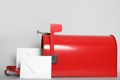 Open red letter box with envelopes on light background