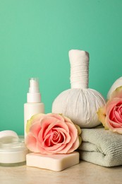 Photo of Composition with different spa products and roses on beige table against turquoise background