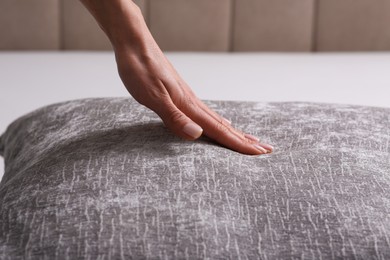 Photo of Woman touching soft light grey pillow on bed, closeup