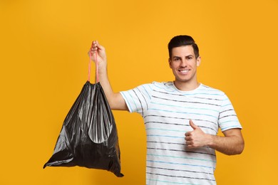 Photo of Man holding full garbage bag on yellow background