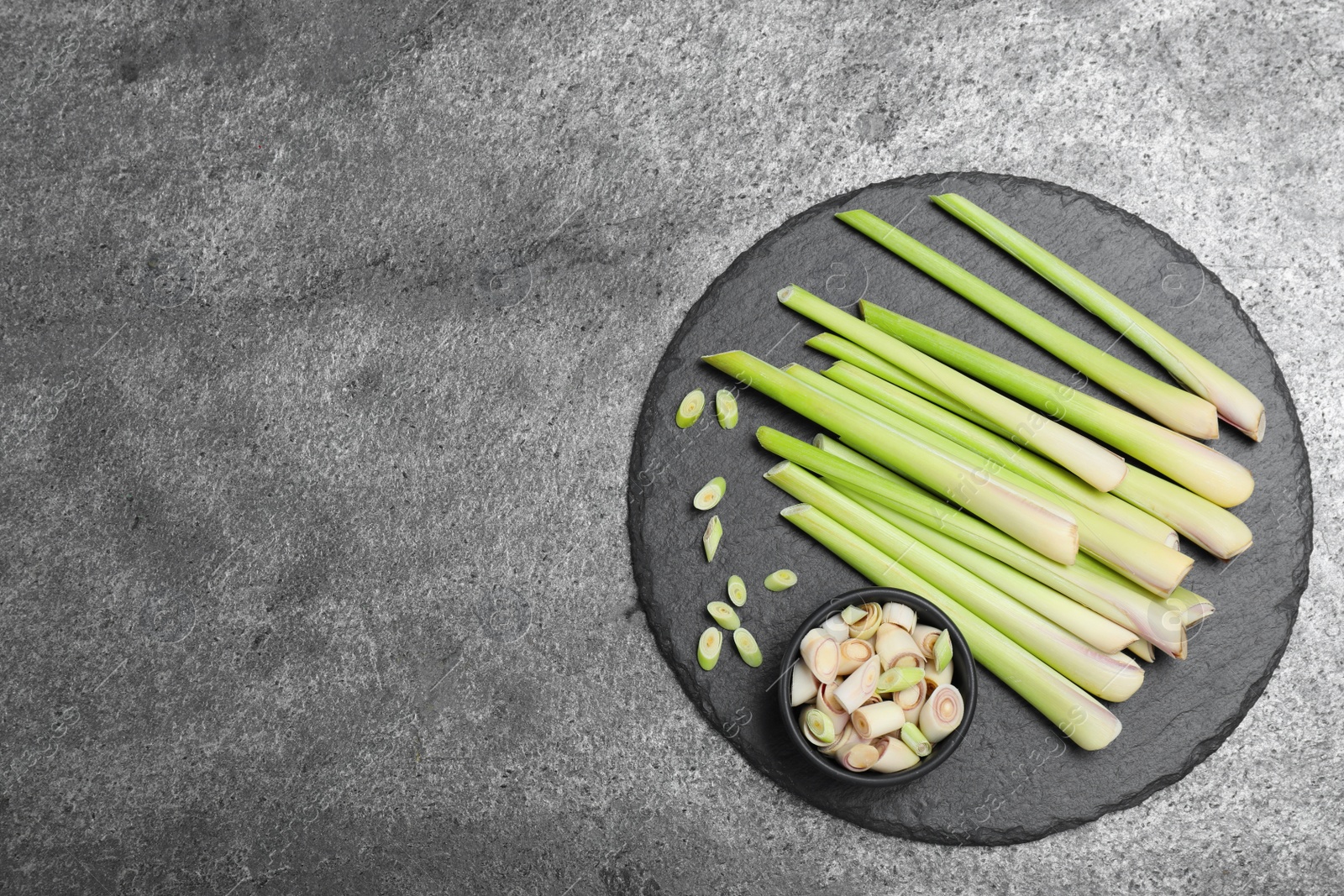 Photo of Fresh lemongrass stalks on grey table, top view. Space for text