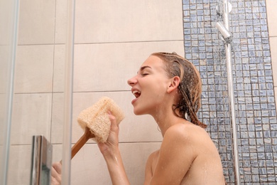 Beautiful young woman singing in shower at home