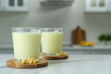 Photo of Tasty fresh corn milk in glasses on white table indoors. Space for text