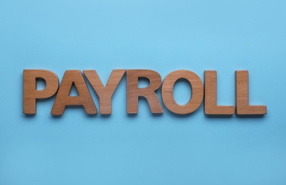 Photo of Word Payroll made with wooden letters on light blue background, flat lay