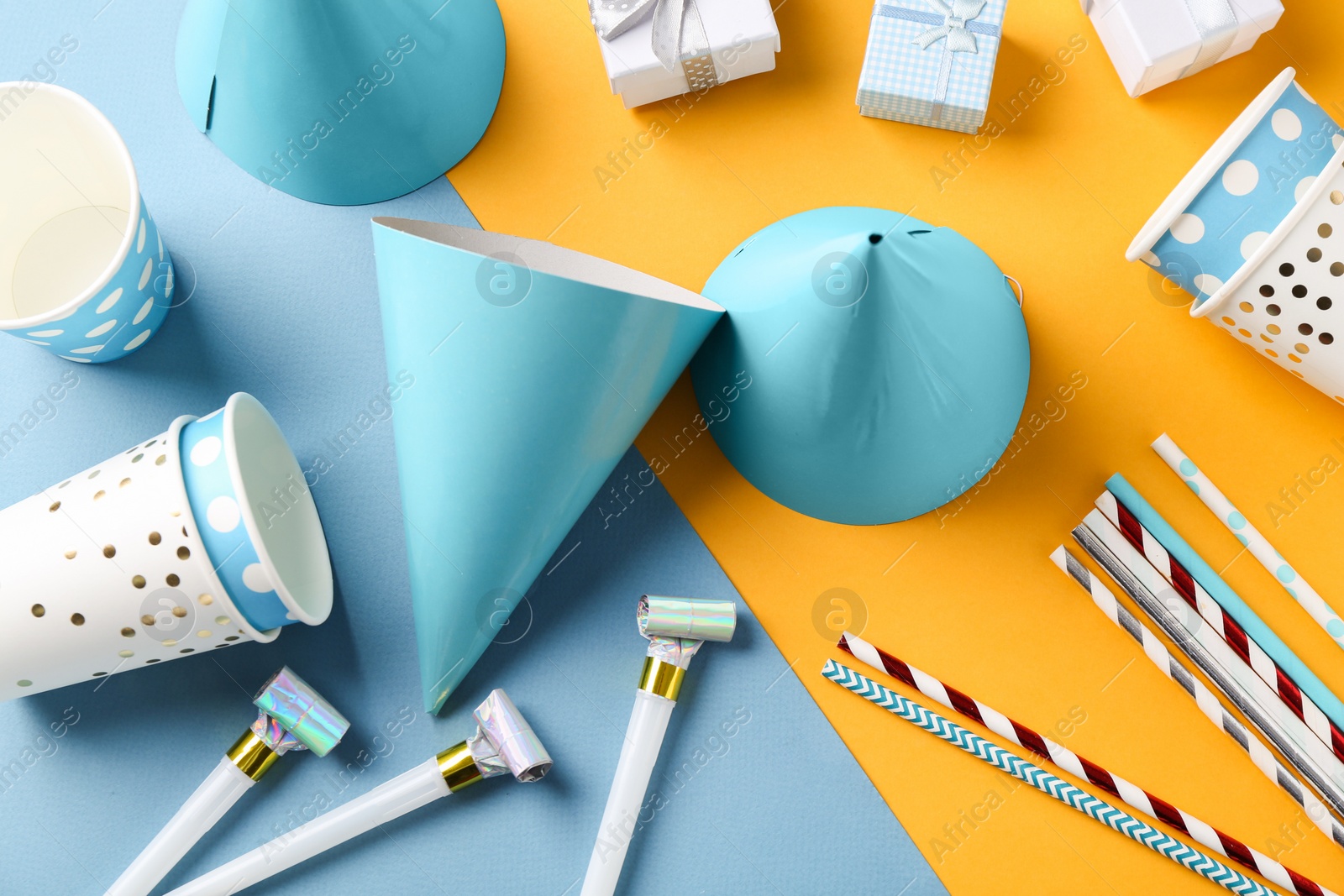 Photo of Party hats and other bright decor on color background, flat lay