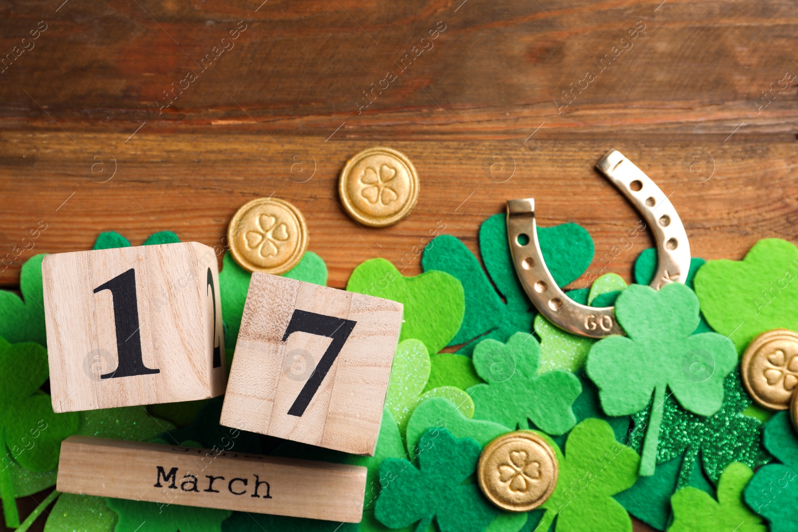 Photo of Flat lay composition with horseshoe and block calendar on wooden background. St. Patrick's Day celebration