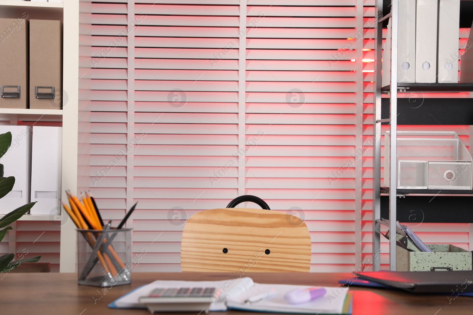 Photo of Stylish office interior with wooden desk, shelving units and stationery