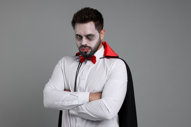 Man in scary vampire costume with fangs on light grey background. Halloween celebration