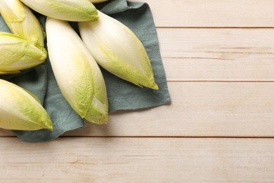 Photo of Raw ripe chicories on wooden table, top view. Space for text