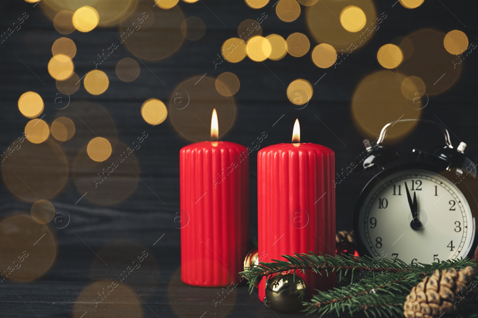 Photo of Alarm clock, burning candles and Christmas decor on wooden table, bokeh effect. Space for text