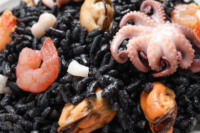 Delicious black risotto with seafood as background, closeup