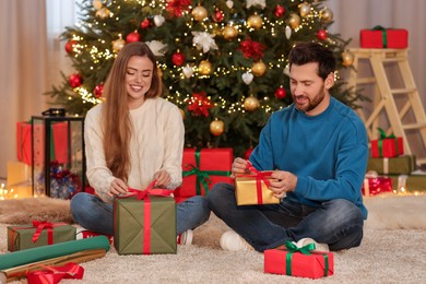 Photo of Happy couple decorating Christmas gifts at home
