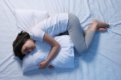 Young woman suffering from insomnia in bed, top view