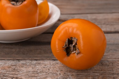 Photo of Delicious ripe persimmon on wooden table, closeup