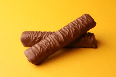 Photo of Sweet tasty chocolate bars on yellow background
