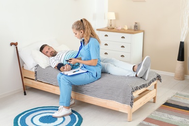 Female medical assistant measuring male patient blood pressure during home visit