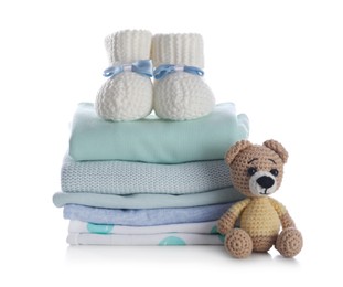 Stack of clean baby's clothes, toy and small booties on white background
