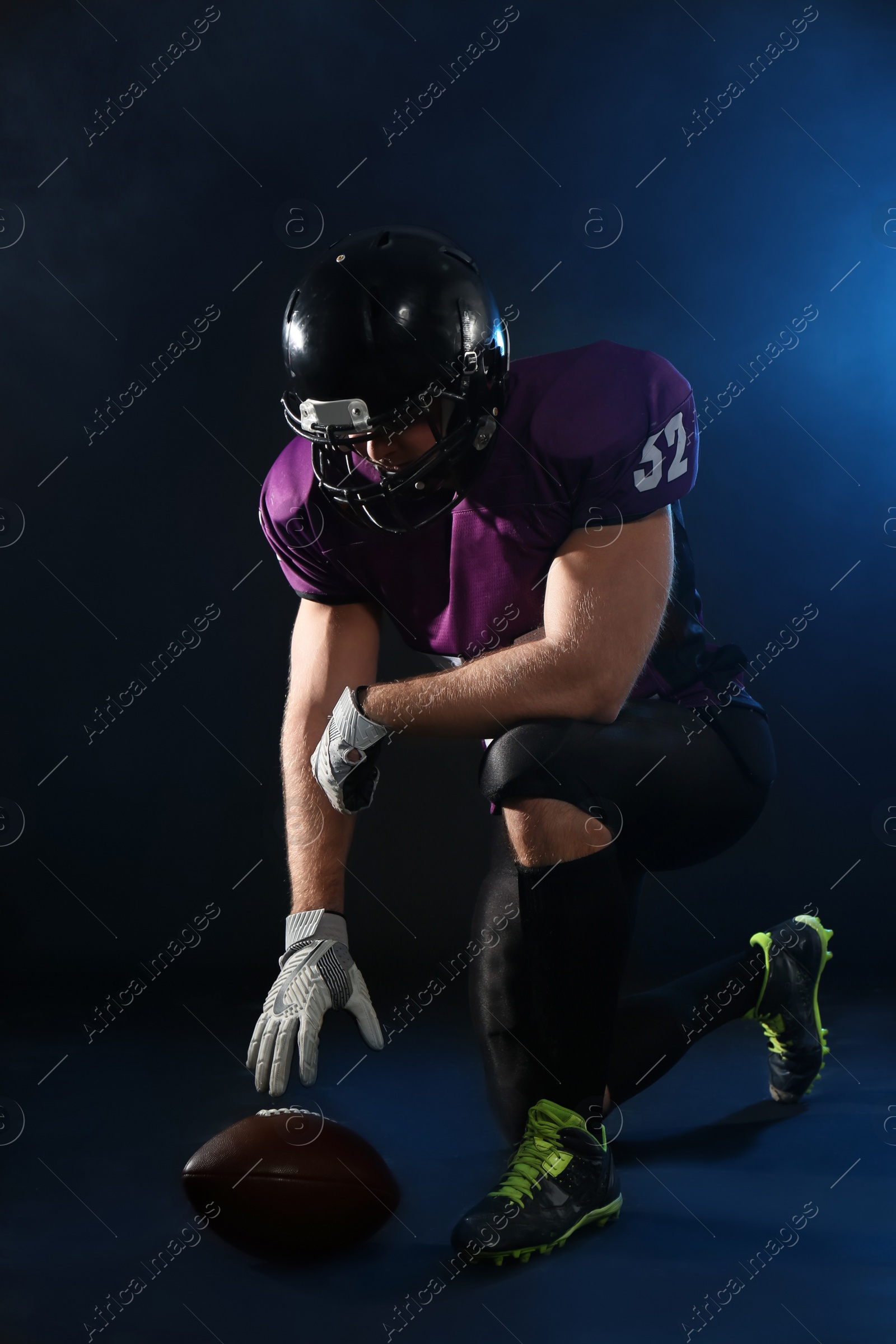 Photo of American football player with ball on dark background