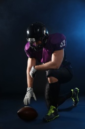 American football player with ball on dark background