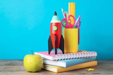 Bright toy rocket and school supplies on wooden desk