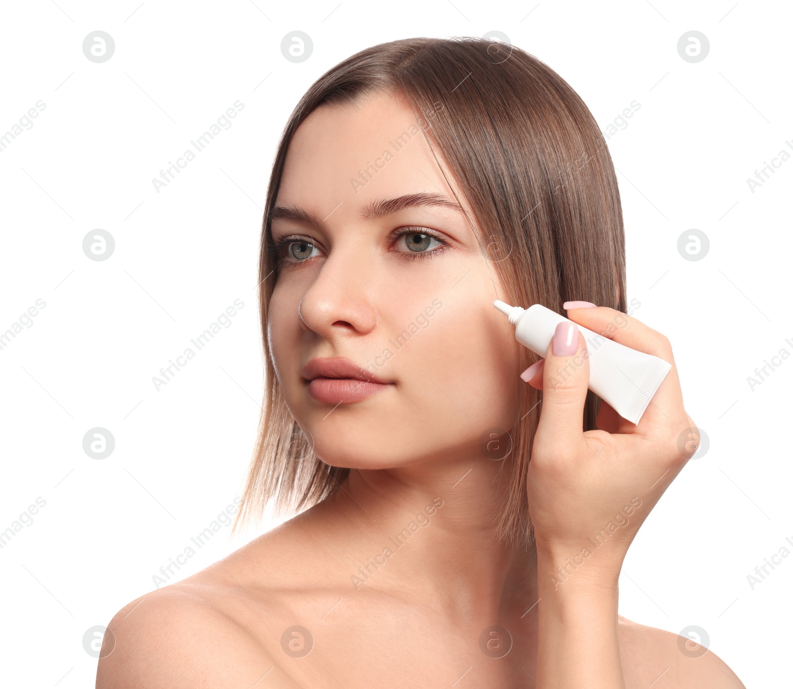 Photo of Young woman applying cream under eyes on white background