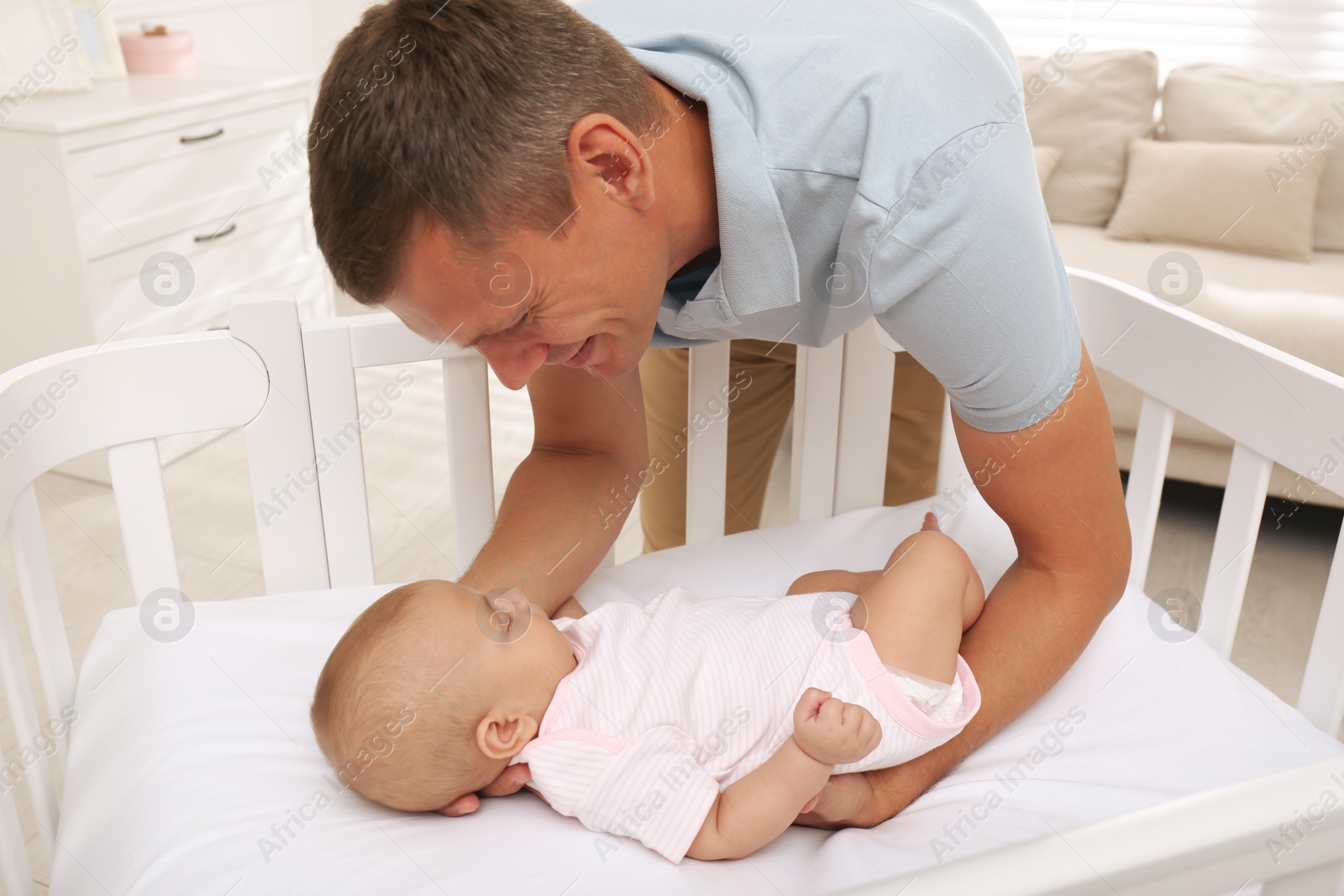 Photo of Happy father near crib with his cute baby at home