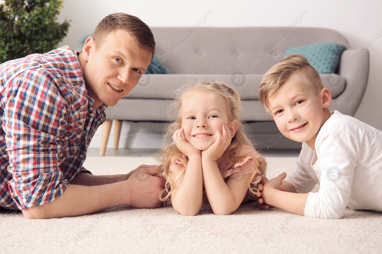 Photo of Cute little children and their father lying on cozy carpet at home