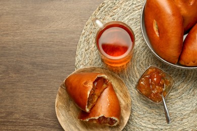 Delicious baked patties with jam and tea on wooden table, top view. Space for text