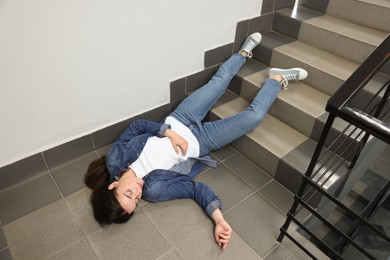 Photo of Unconscious woman lying on floor after falling down stairs indoors