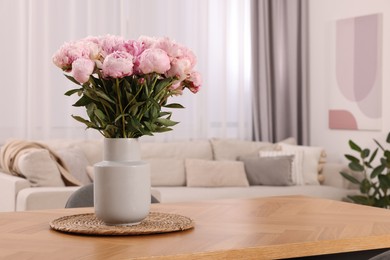 Vase with pink peonies on wooden table in dining room. Space for text