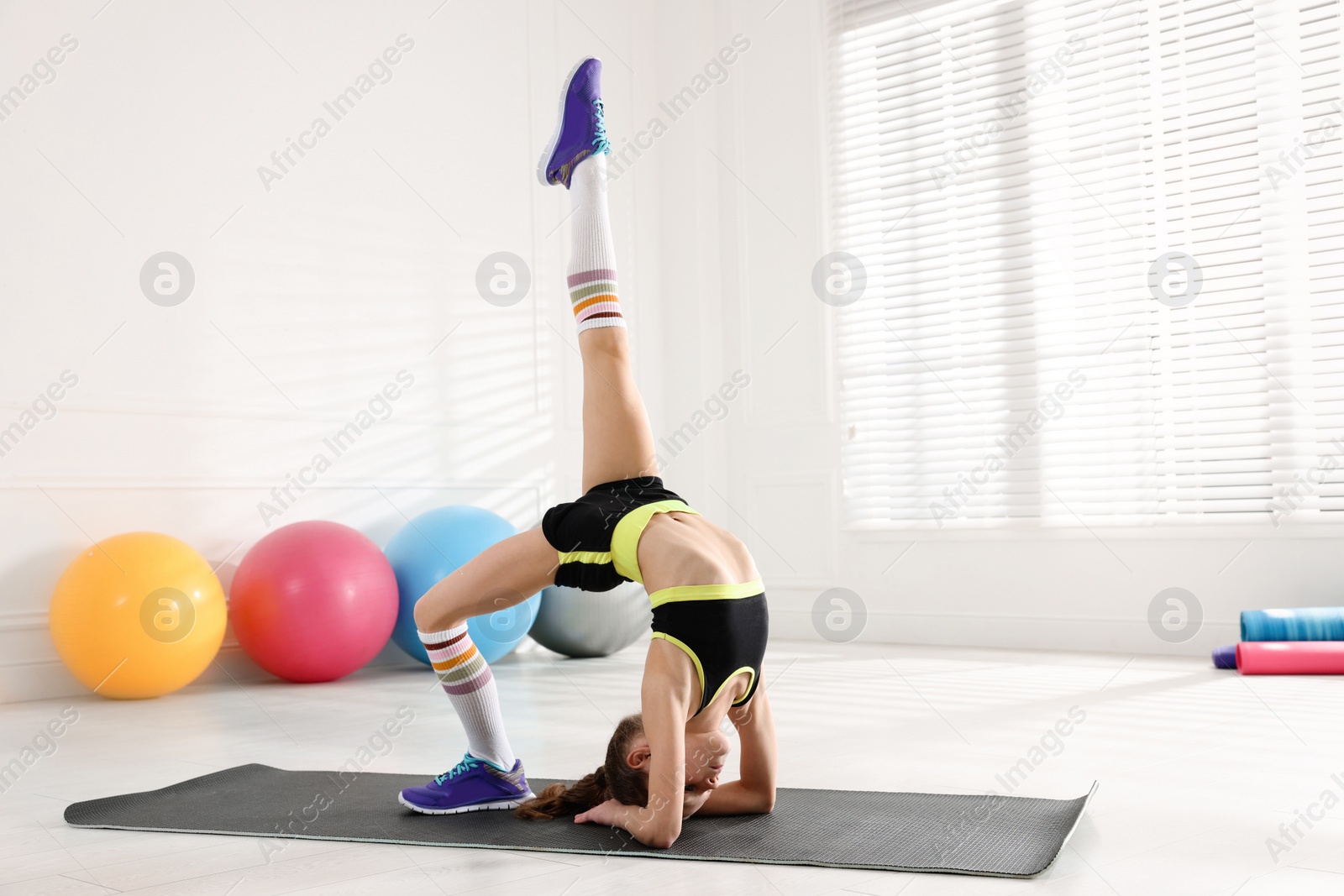 Photo of Cute little girl doing gymnastic exercise indoors