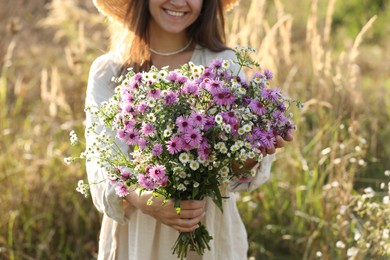 Photo of Woman holding bouquet of beautiful wild flowers outdoors, closeup