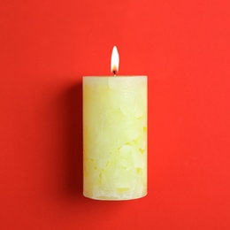 Alight scented wax candle on color background